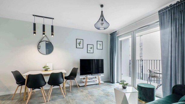 A modern living room with a dining area, a flat-screen TV, and a balcony with a view. - Lumina airy apart near Manufaktura (Łódź)