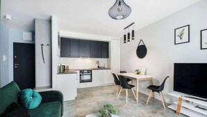 A modern apartment with a kitchen, dining area, living room, and a TV. - Lumina airy apart near Manufaktura (Łódź)