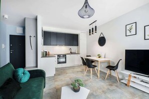 Un appartement moderne comprenant une cuisine, un coin repas, un salon et un téléviseur.