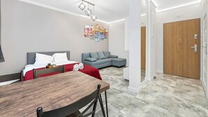 Un salon moderne avec un canapé gris, une table à manger en bois et un plaid rouge.