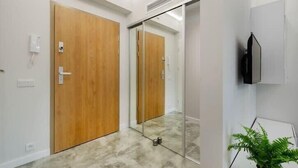 Un couloir avec des portes en bois, un miroir, un téléviseur et une plante en pot.