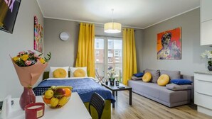 A modern hotel room with a bed, a sofa, a dining table, and a TV. - Lumina modern studio with balcony (Łódź)