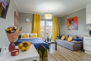A modern hotel room with a bed, a sofa, a dining area, and a window with curtains. - Lumina modern studio with balcony (Łódź)