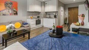A modern apartment with a kitchenette, a dining area, and a living room with a sofa and coffee table. - Lumina modern studio with balcony (Łódź)