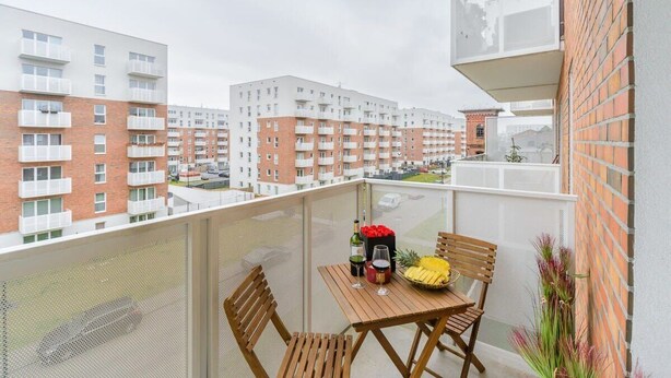 A balcony with a table, chairs, and a view of apartment buildings. - Lumina modern studio with balcony (Łódź)