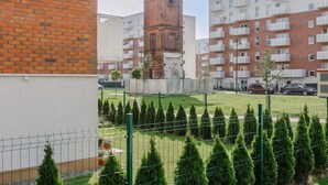 A residential building with a brick tower, a fenced garden, and multiple balconies. - Lumina modern studio with balcony (Łódź)