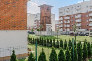 A residential building with a brick tower, multiple balconies, and a fenced garden area. - Lumina modern studio with balcony (Łódź)