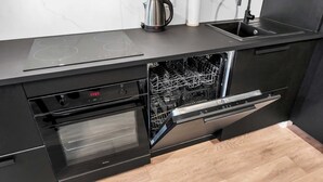 Una cocina moderna con lavavajillas integrado, horno y hervidor sobre la encimera.