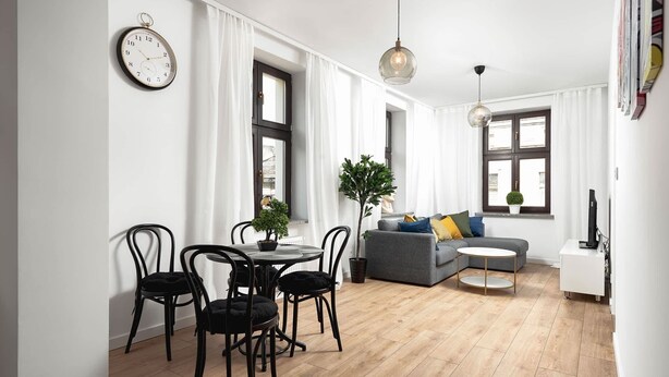 Ein modernes Wohnzimmer mit Essbereich, einem grauen Sofa und einem kleinen Tisch.