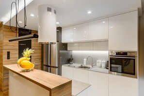 A modern kitchen with stainless steel appliances, a wooden countertop, and a built-in oven.