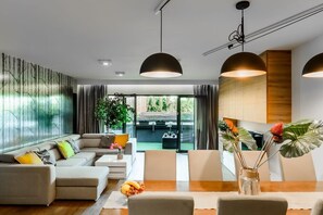 A modern living room with a sectional sofa, a dining table, and pendant lighting. - Lumina stylish 2-level apart next to Księży Młyn (Lódz)