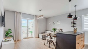 Una cocina moderna con comedor, ventanas amplias y vistas a edificios.