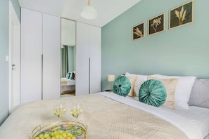 Quarto com cama, mesa de cabeceira, espelho e parede com quadros.