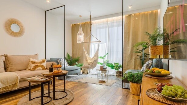 Een moderne woonkamer met een bank, salontafel en een eethoek met schalen vol fruit.