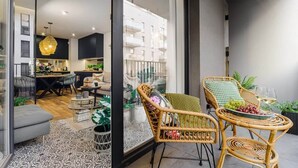 Een moderne woonruimte met een eethoek, rieten stoelen en uitzicht op een woongebouw.