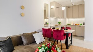 Una sala de estar moderna con un sofá, una mesa de comedor con sillas y una zona de cocina con armarios y una encimera.