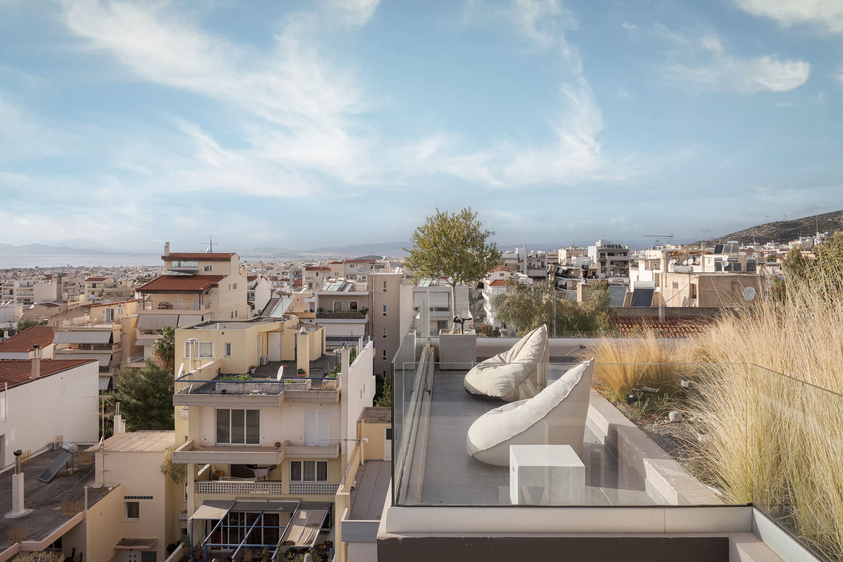A rooftop terrace with a view of a cityscape, featuring modern buildings and a clear sky.