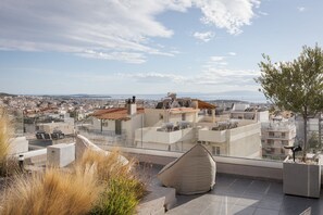 A rooftop terrace with a clear view of the cityscape, including buildings and distant mountains. - Glyfada Panoramic Penthouse (Glyfada)
