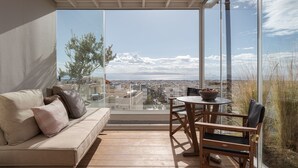 Un balcón con sofá y mesa, que ofrece vistas a la ciudad y al mar.