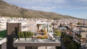 Un moderno complejo de apartamentos con terrazas en la azotea, vistas a una colina y cielo despejado.