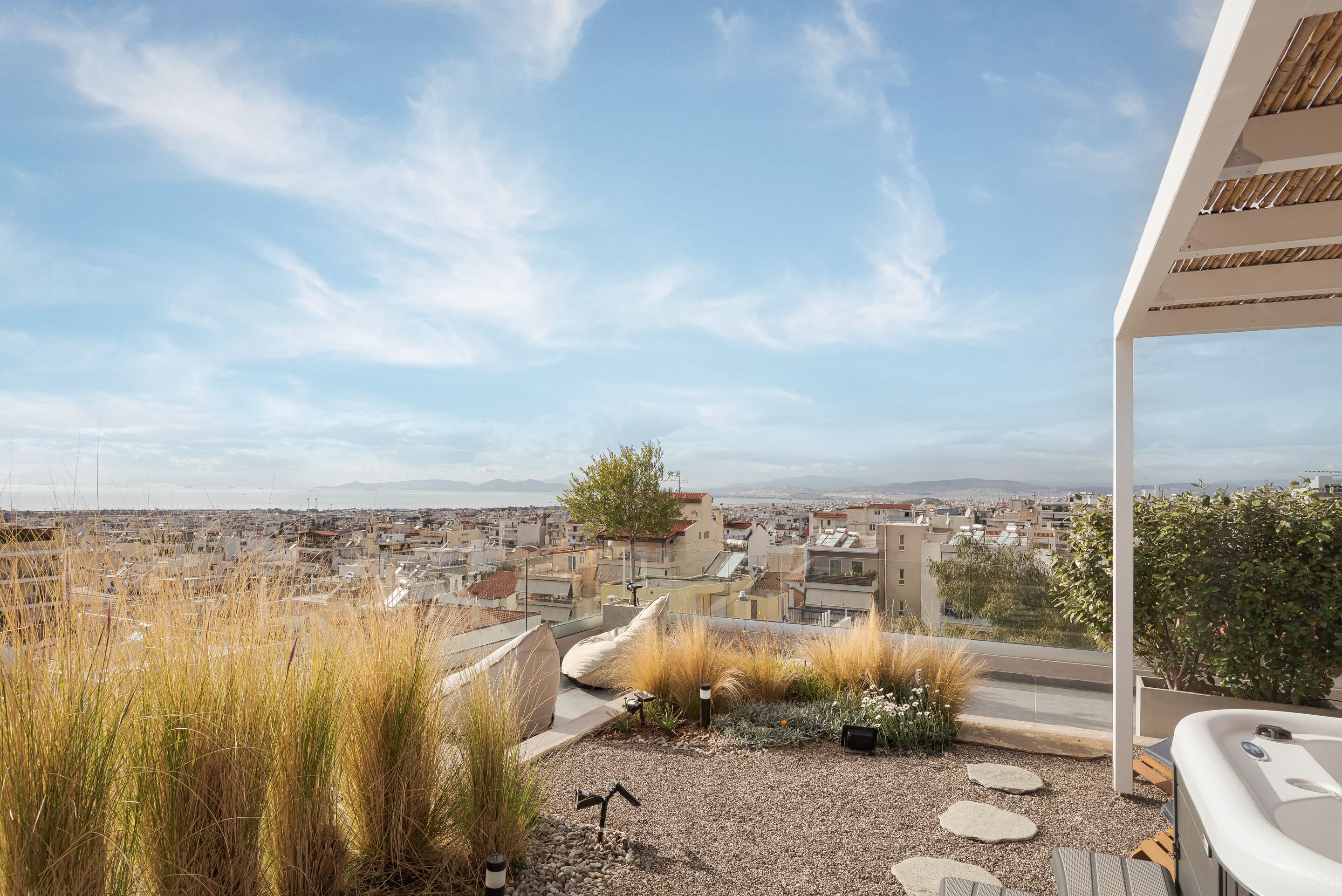 A rooftop terrace with a view of a cityscape, including buildings and a tree.