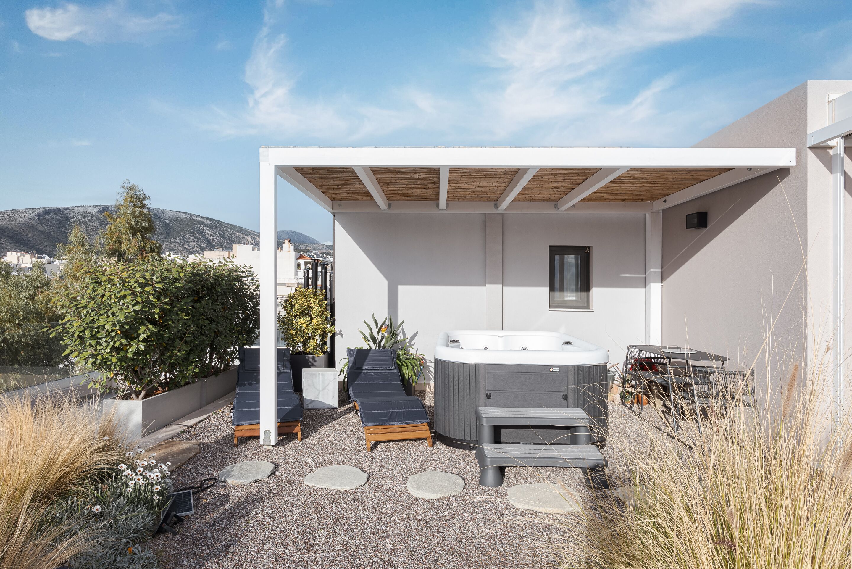 Una terrazza sul tetto con vasca idromassaggio, poltrone relax e un pergolato.