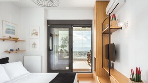 Un dormitorio moderno con cama, televisor, puerta corrediza al balcón y vistas a la ciudad.