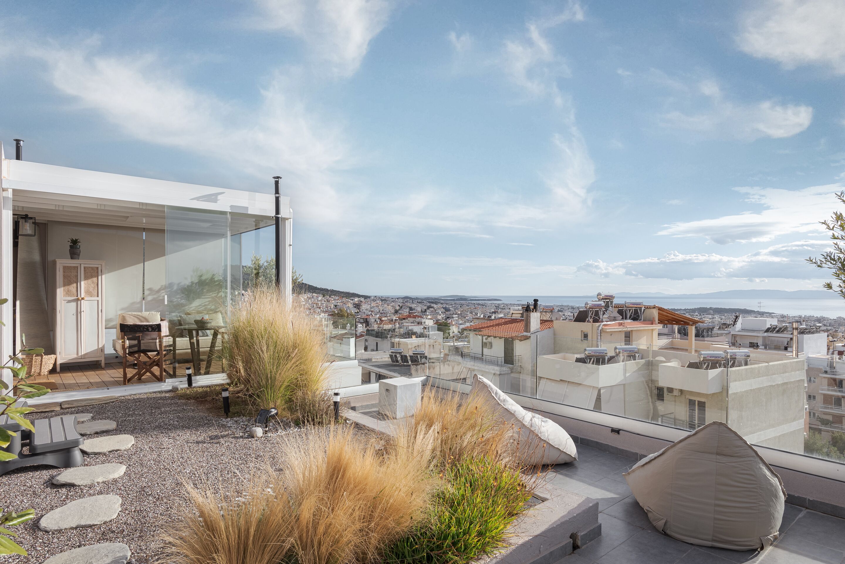 A rooftop terrace with a modern glass enclosure, outdoor seating, and a view of the cityscape.