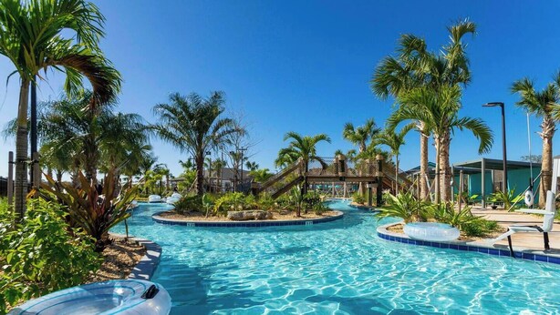 Uma área de piscina com várias piscinas, palmeiras e espreguiçadeiras.