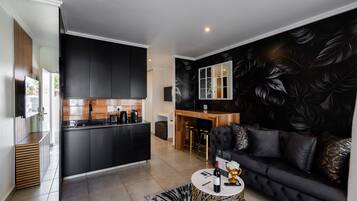 A modern living space with a kitchen, dining area, and a black leather sofa.