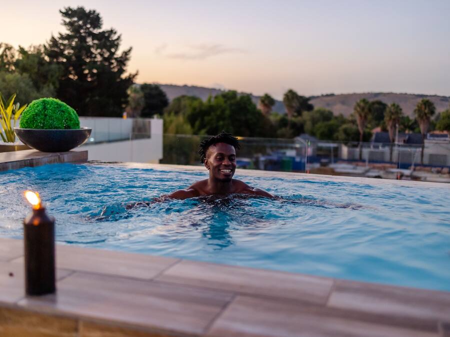 Una piscina con alguien nadando, una vela en el borde y una planta en maceta.
