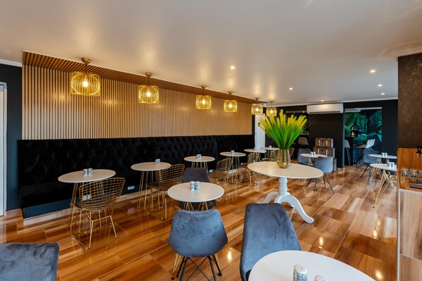 Un intérieur de restaurant moderne avec des tables rondes, des sièges rembourrés et un éclairage décoratif.
