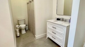 Ein Badezimmer mit Toilette, Dusche und Waschtisch mit Spiegel.