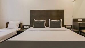 A hotel room with two single beds, a large bed, and a wooden headboard.