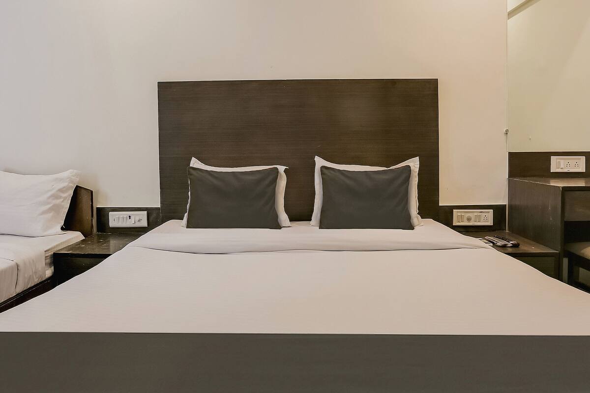Ein Hotelzimmer mit zwei Einzelbetten, einem großen Bett und einem Holzkopfstück.