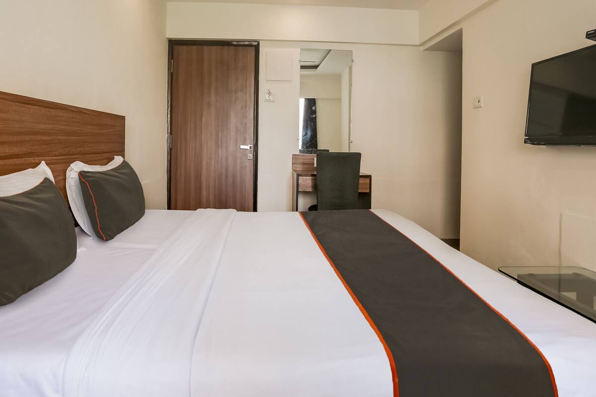 Ein Hotelzimmer mit einem großen Bett, einem Holz-Kopfteil, einem flachbildschirmfernseher an der Wand und einem Schreibtisch mit Stuhl.