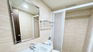 Een badkamer met een witte wastafel, een spiegel, een toilet en een douchehoek.