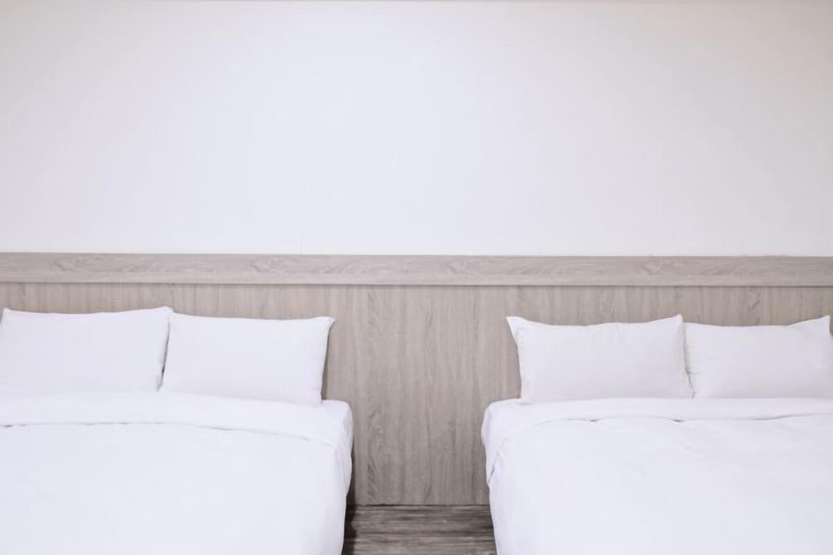A double bed with white bedding and a wooden headboard.