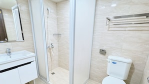 Een moderne badkamer met een glazen douchecabine, een wit wastafelmeubel en een toilet.