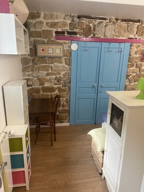 Cozy room with a rustic charm, featuring a stone wall and a blue door. A wooden chair and small table offer a space for dining or working.