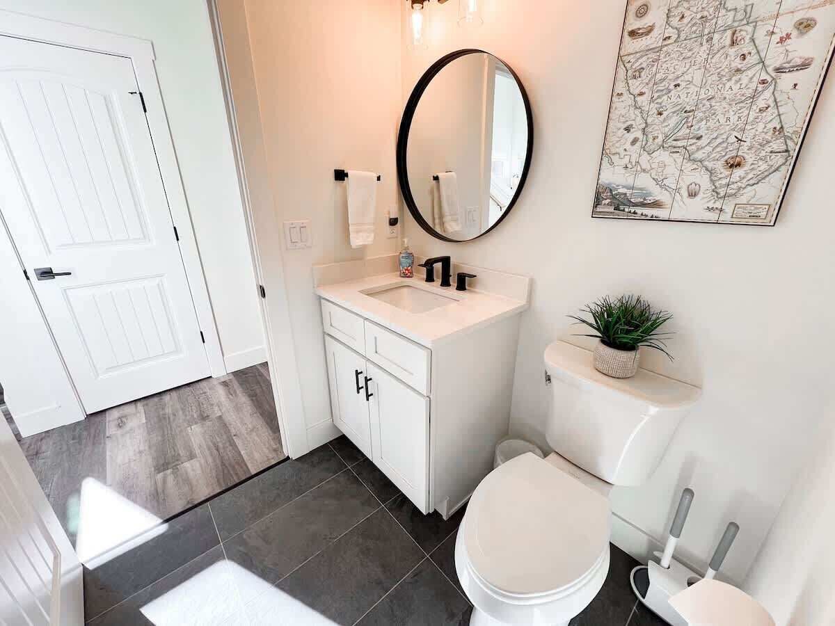 Un baño con un inodoro blanco, un lavamanos blanco con un espejo encima y un mapa en la pared.
