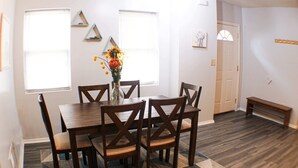 A dining area with a wooden table and chairs, a vase with flowers, and a patterned rug. - Carey Way Quarters – Modern 2BR Near Carson Street (Pittsburgh)