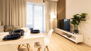 A modern living room with a dining area, a flat-screen TV, and a large plant. - Campo Twoja Oaza w Shellter Rogowo (Trzebiatow)