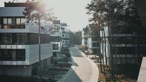 A modern building complex with multiple floors, a curved pathway, and surrounding trees. - Campo Twoja Oaza w Shellter Rogowo (Trzebiatow)