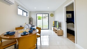 A modern kitchen with a dining table, chairs, and a TV. - Royal Lake Guest House (Toukley)