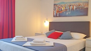 A hotel room with a bed, a painting on the wall, and a red curtain. - Holiday Home Gordana - Charming Deluxe Apartment in fabulous Hvar (HVAR (HVAR))