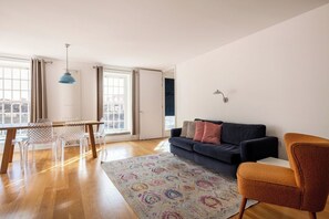 A spacious living room with a dark blue sofa, a wooden coffee table, and a patterned rug.