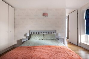 A bedroom with a bed, nightstands, a window, and a door.