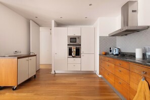 A modern kitchen with a microwave, oven, and a coffee maker on the counter.