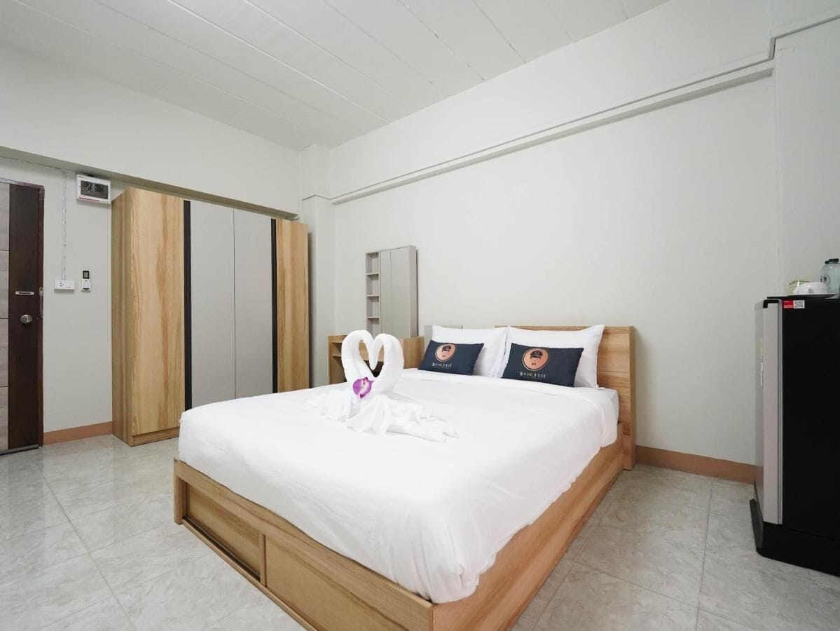 A hotel room with a bed, a wardrobe, a desk, and a refrigerator.